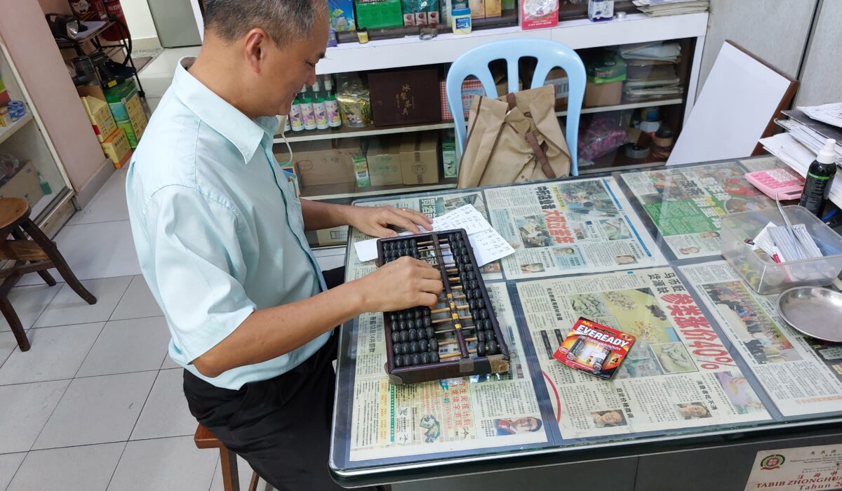 Shop owner counts herb prices on an abacus